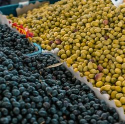 A vibrant selection of black and green olives at an outdoor market stall.