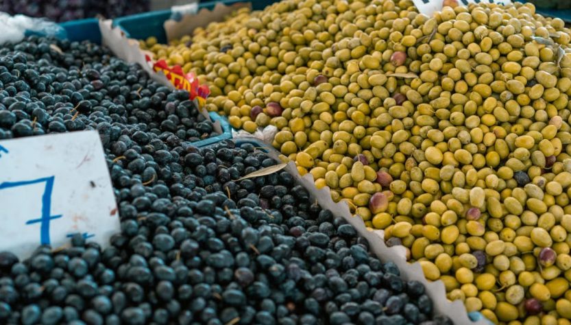 A vibrant selection of black and green olives at an outdoor market stall.