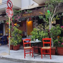 Outdoor café with colorful chairs and lush plants in Heraklion, Greece.