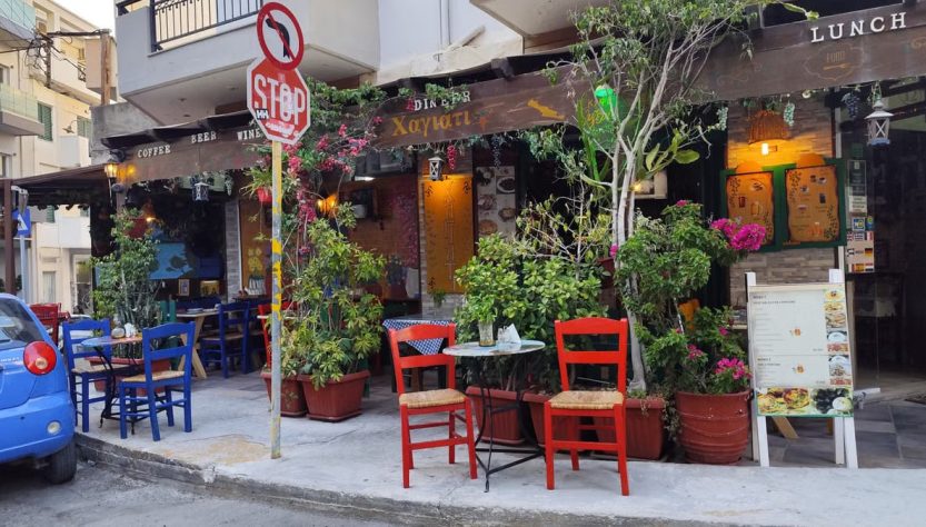 Outdoor café with colorful chairs and lush plants in Heraklion, Greece.